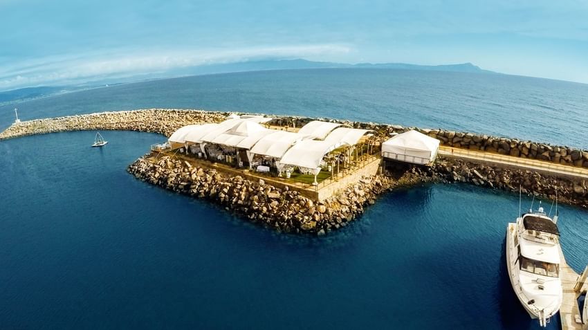 Outdoor wedding venue at Hotel Coral y Marina, with white tents on a rocky pier stretching into the ocean