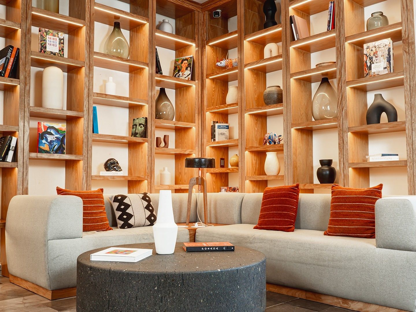 Cozy seating area with orange pillows and backlit shelves in Library Café & Deli at Camino Real Zaashila Huatulco