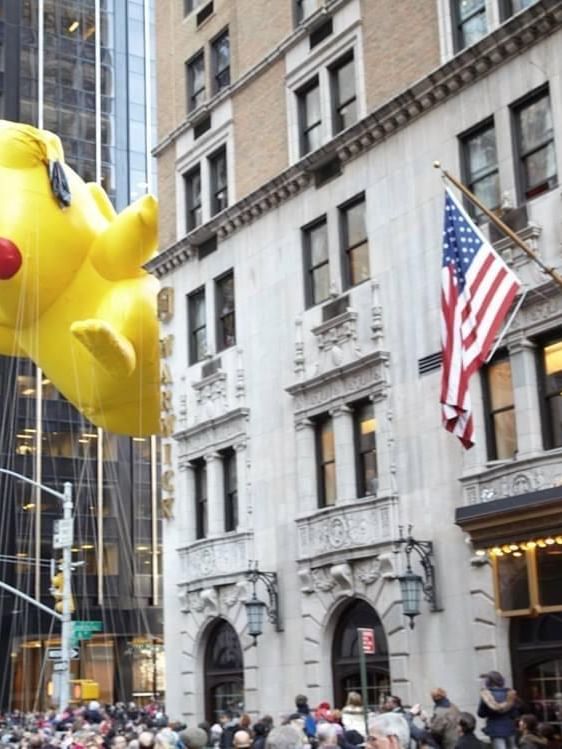 Massive Pikachu parade balloon glides through the air past the Warwick Hotel entrance