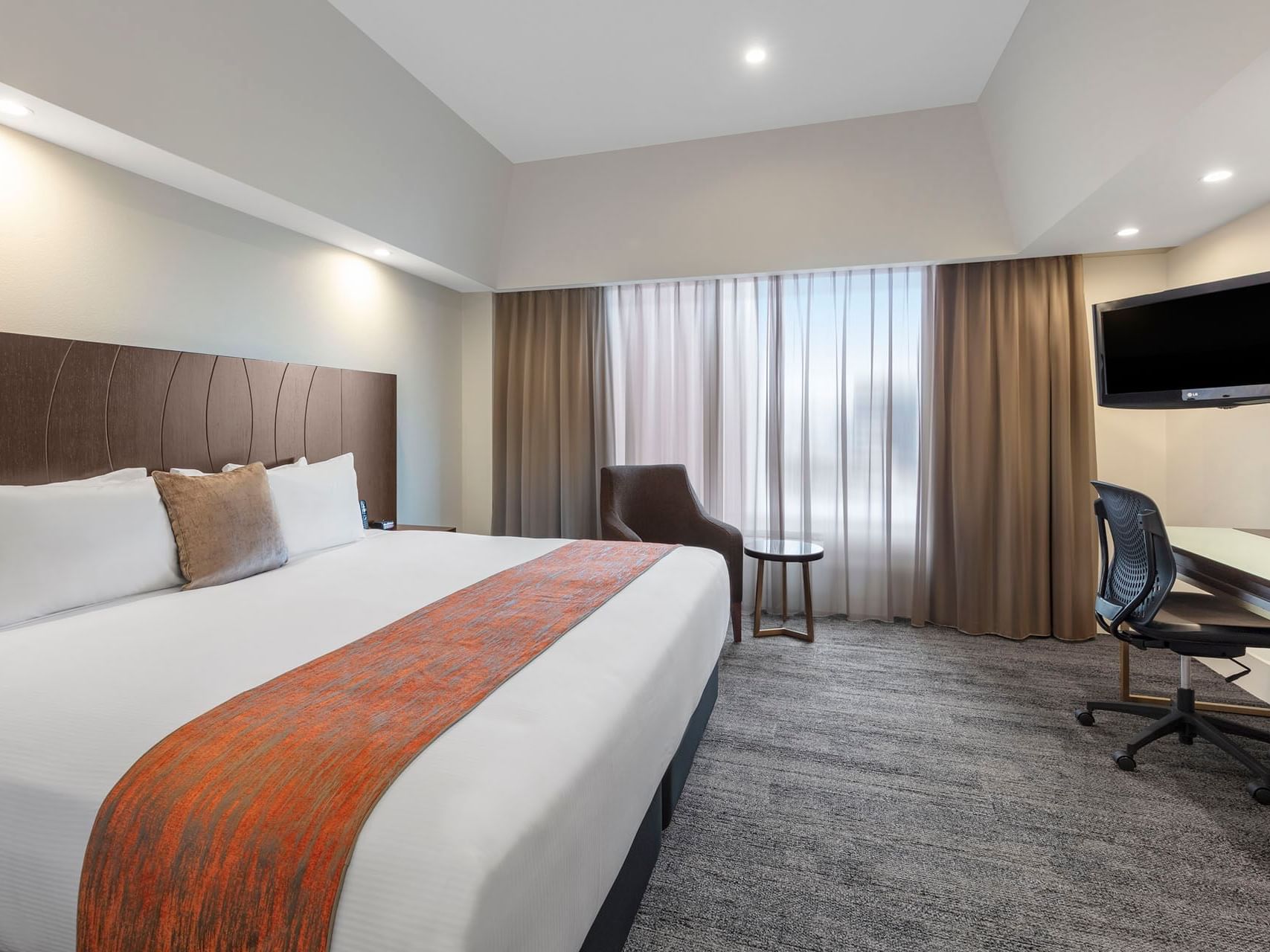 King bed, desk & chair in a room at James Cook Grand Chancellor