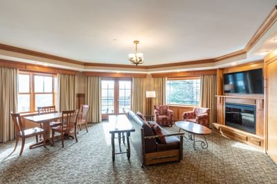 Suite living area at Lake Placid Club Grandview featuring a fireplace, TV, sitting area and dining table with balcony access