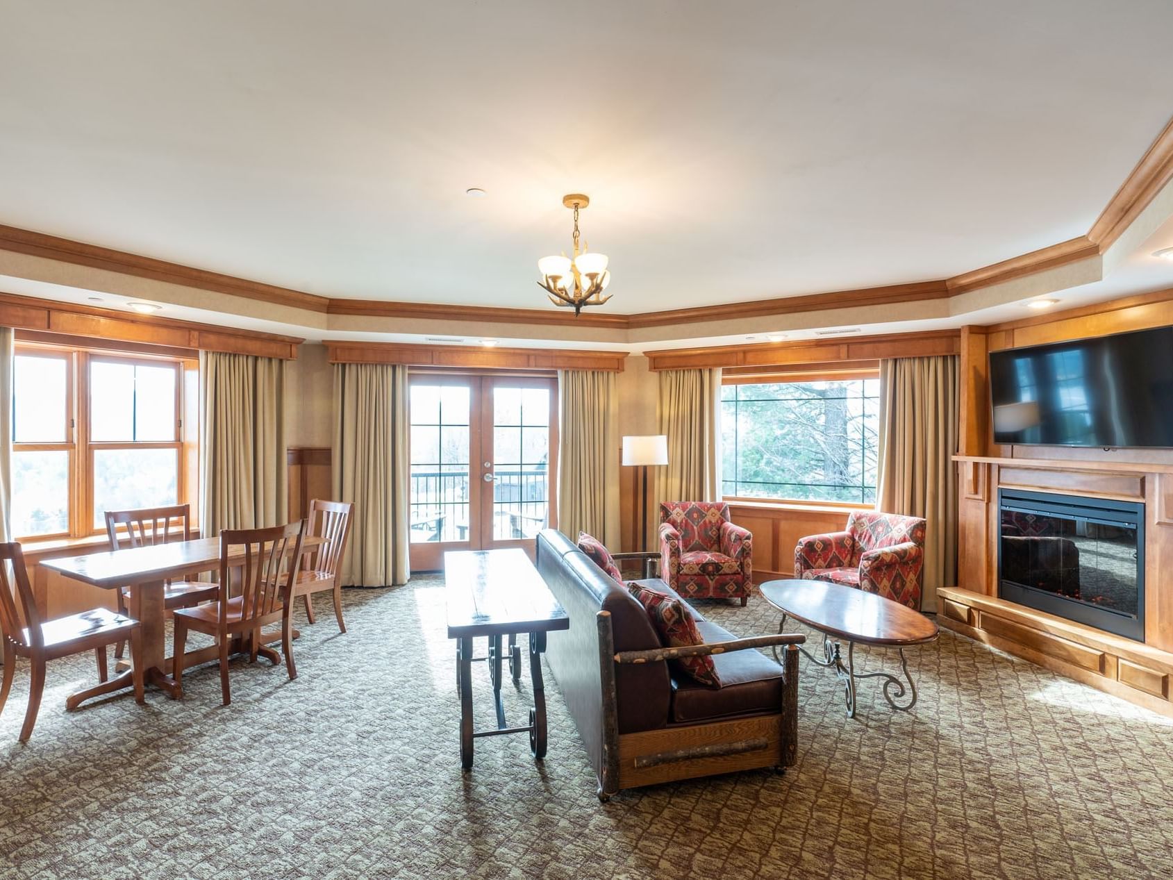 Suite living area at Lake Placid Club Grandview featuring a fireplace, TV, sitting area and dining table with balcony access
