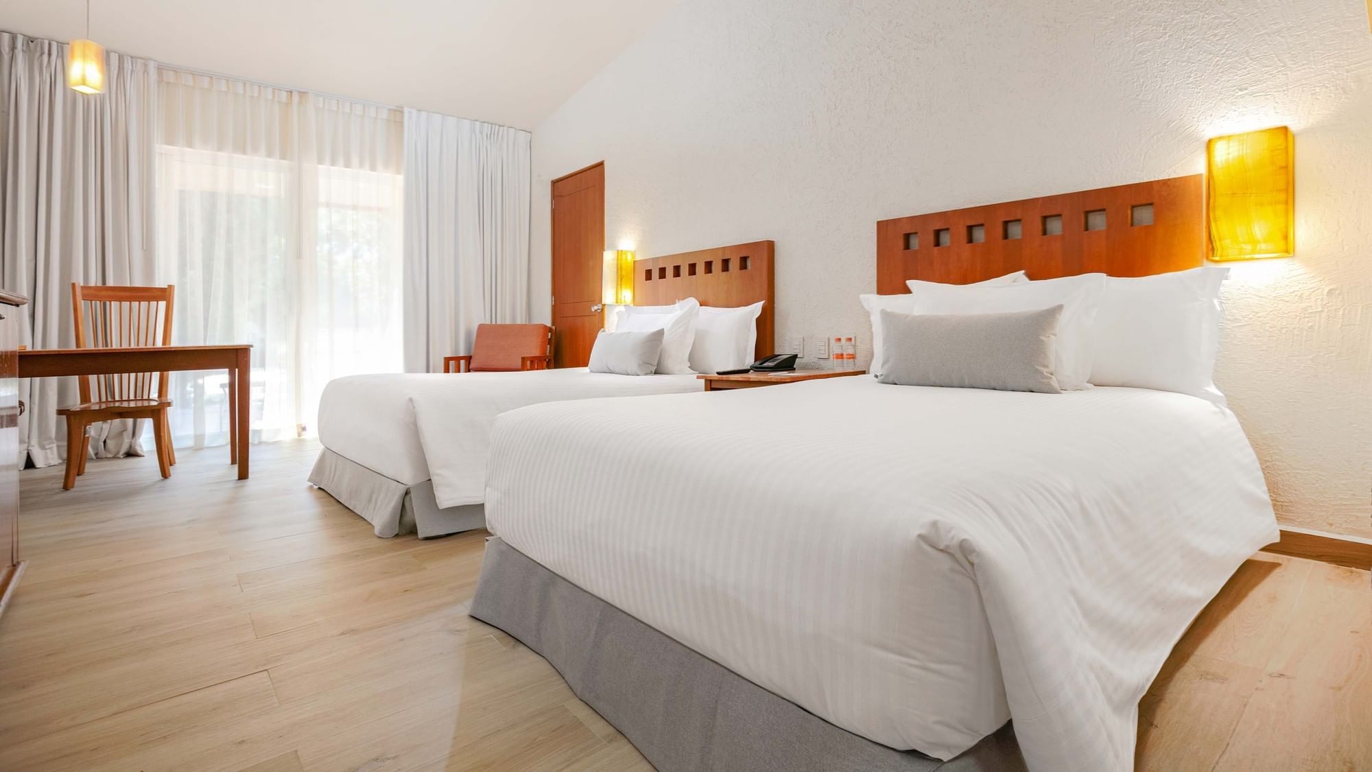Two double beds with white linens in a room at Camino Real Guadalajara in Zapopan