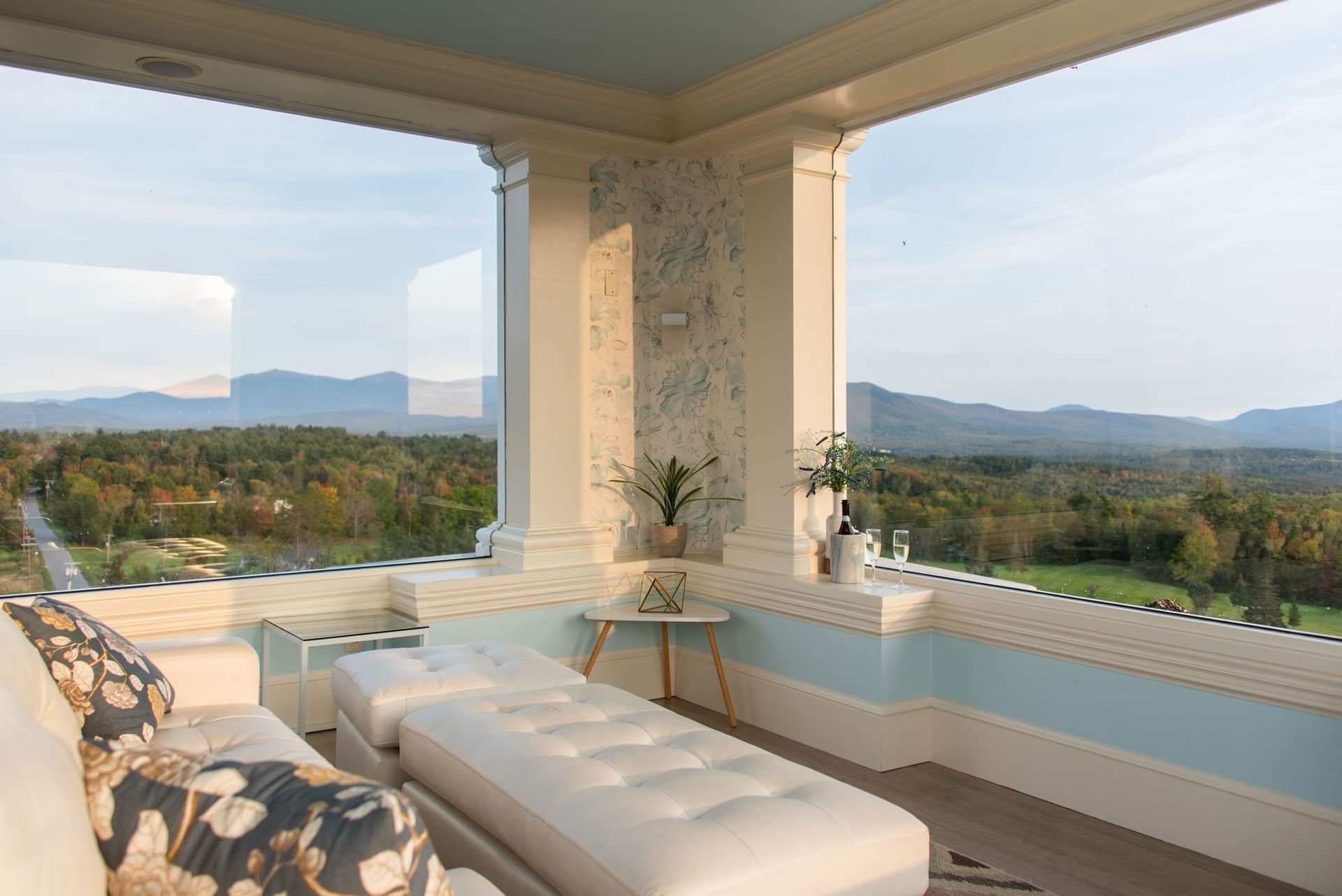 White lounge chairs beside large windows facing panoramic mountain views at Mountain View Grand Resort & Spa