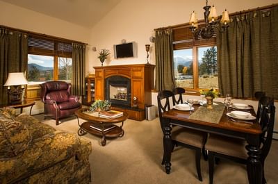 Living area with a fireplace, leather armchair, dining table, and large windows with a scenic view at The Stanley Hotel