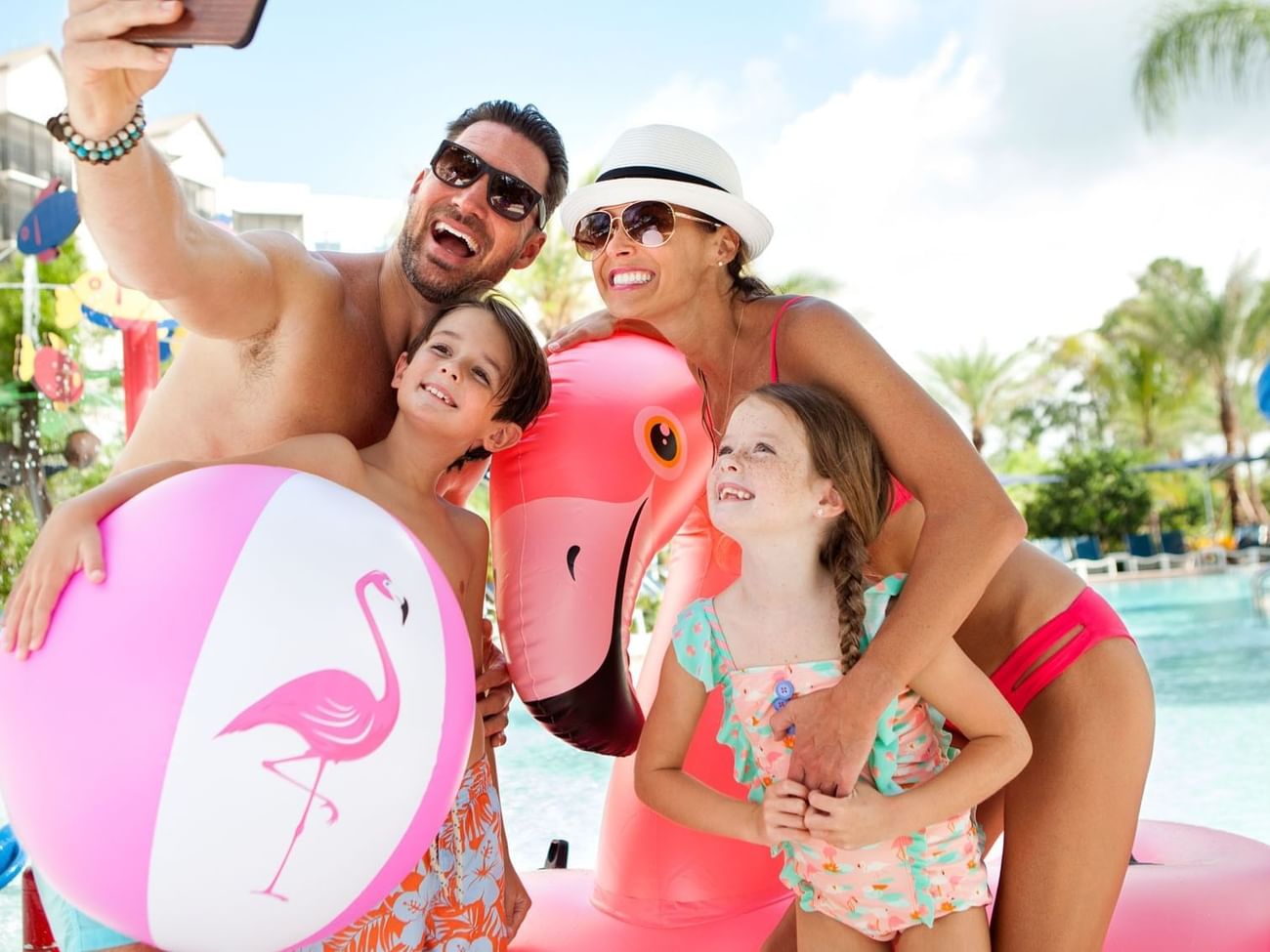 Family taking a selfie with inflatable flamingo toys in Surfari Water Park at The Grove Resort & Water Park