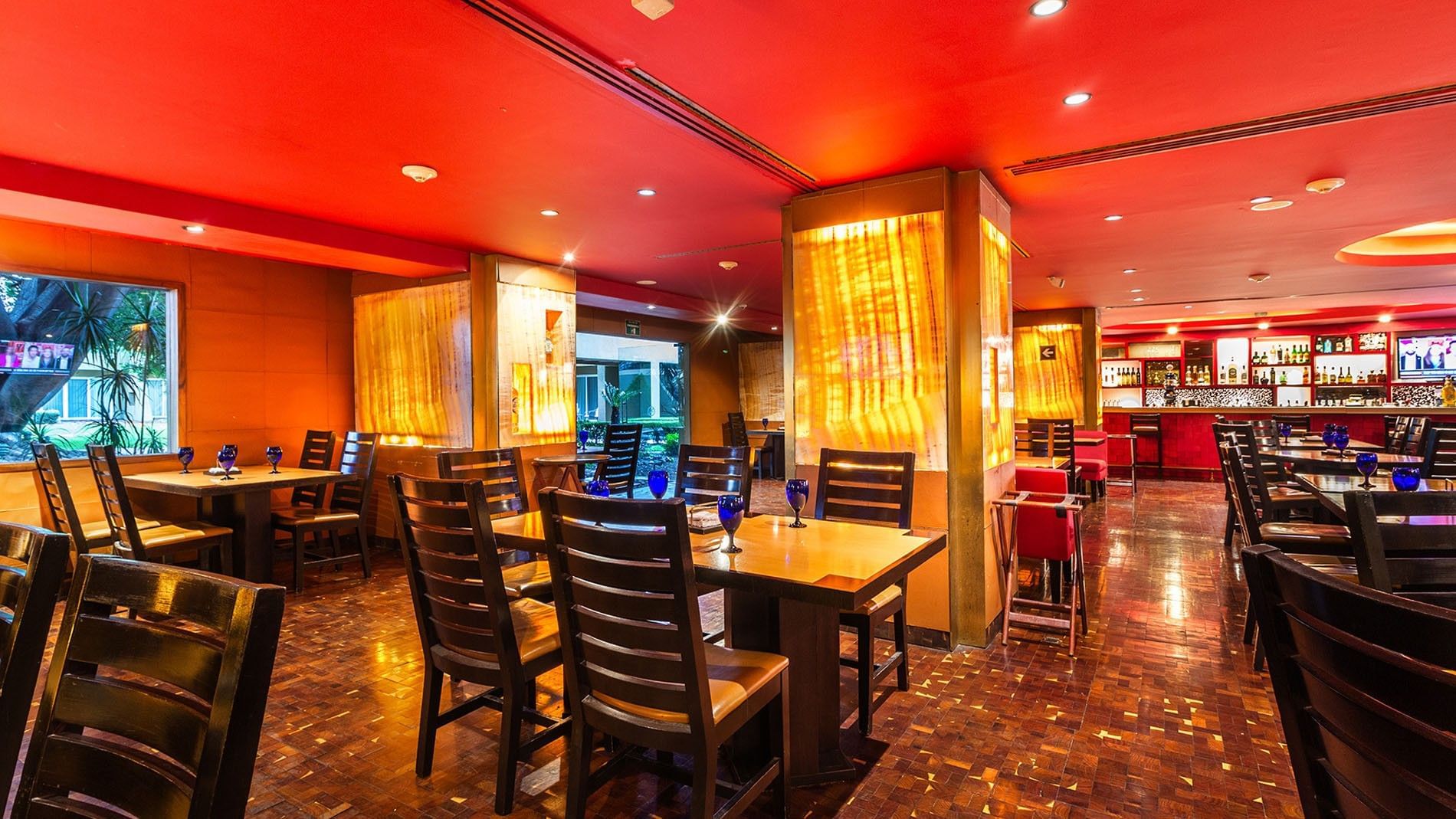 Maria Bonita dining room with glowing amber pillars and a vibrant red ceiling at Camino Real Guadalajara
