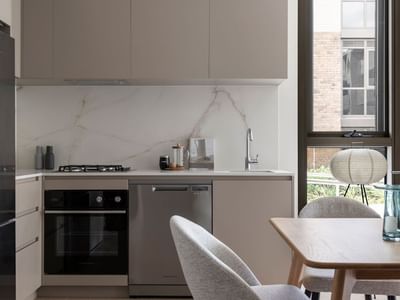 Modern kitchen with marble backsplash, stainless steel appliances, and dining area with wooden table and chairs.