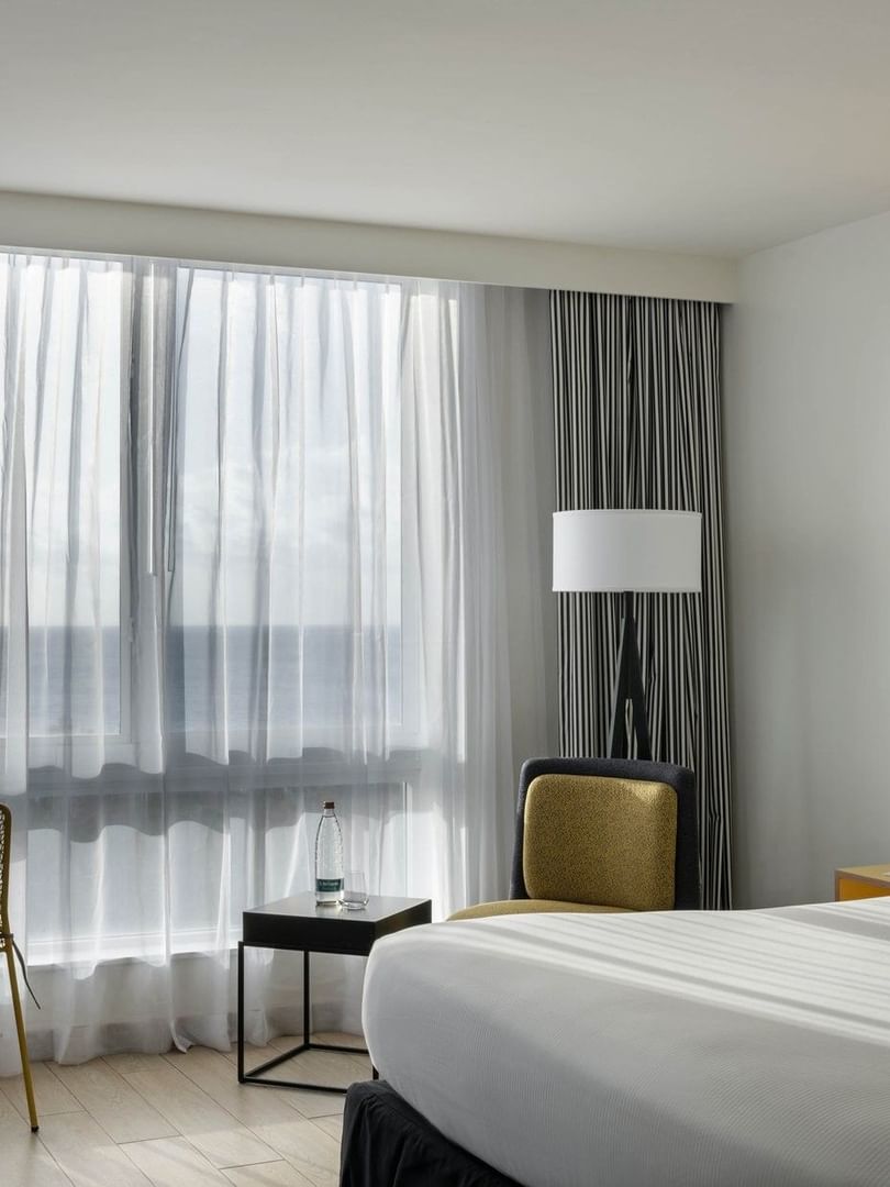 Pillows on a bed by a black side table under a wall sconce in water view at Warwick Paradise Island Bahamas