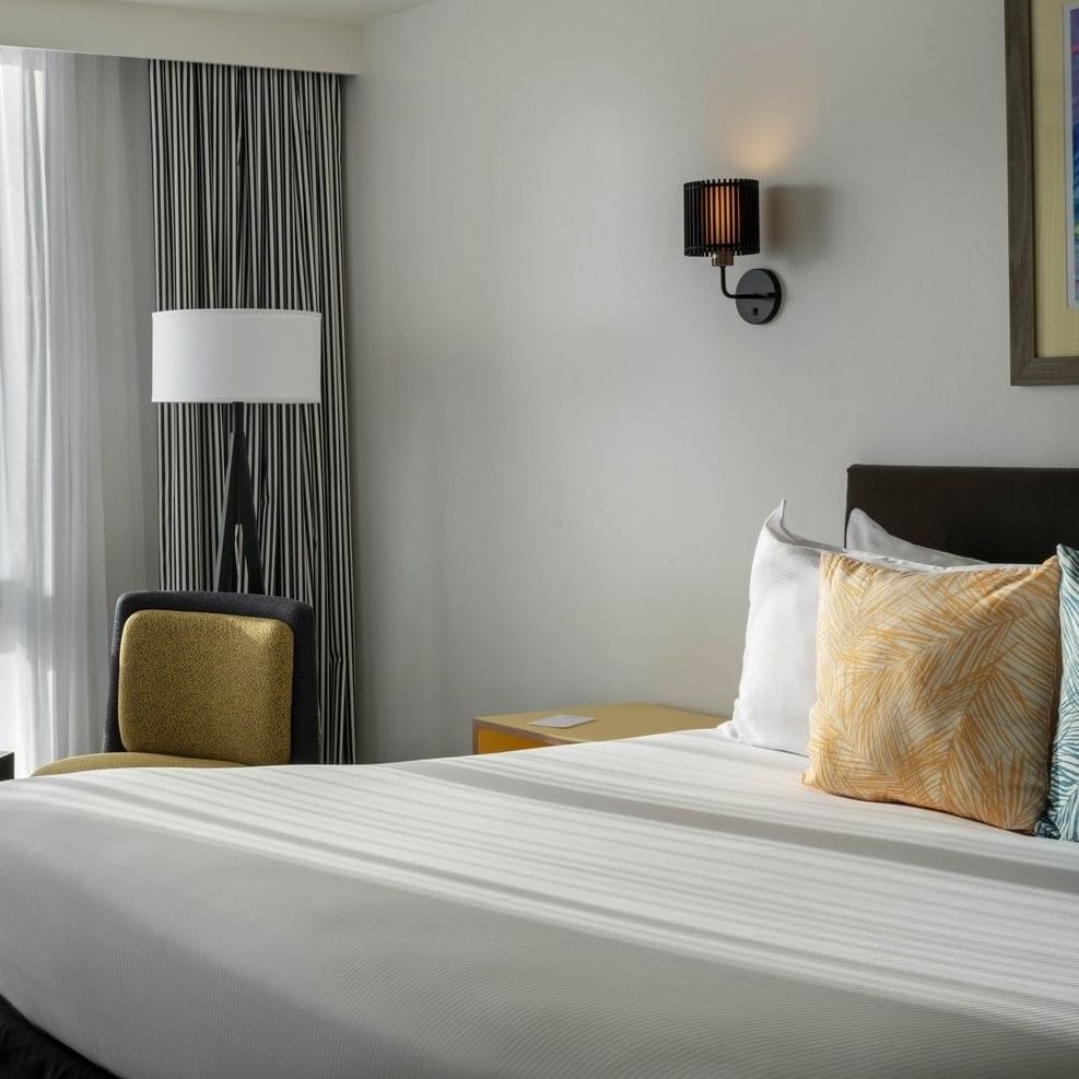 Pillows on a bed by a black side table under a wall sconce in water view at Warwick Paradise Island Bahamas