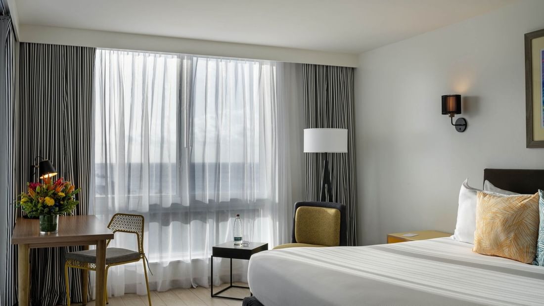 Pillows on a bed by a black side table under a wall sconce in water view at Warwick Paradise Island Bahamas