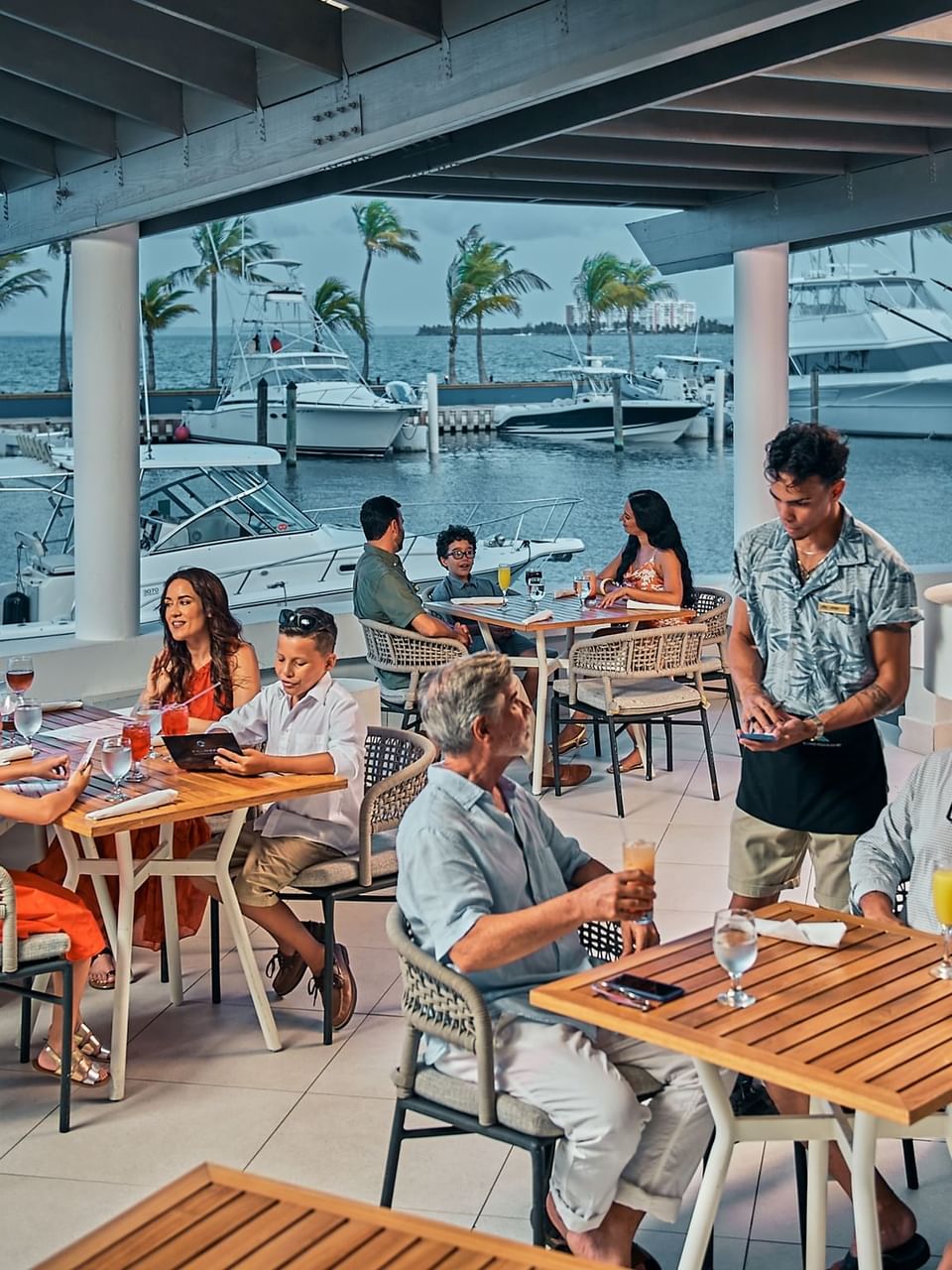 Personas cenando con vista al mar y botes amarrados en Ballyhoo en Las Casitas Village.