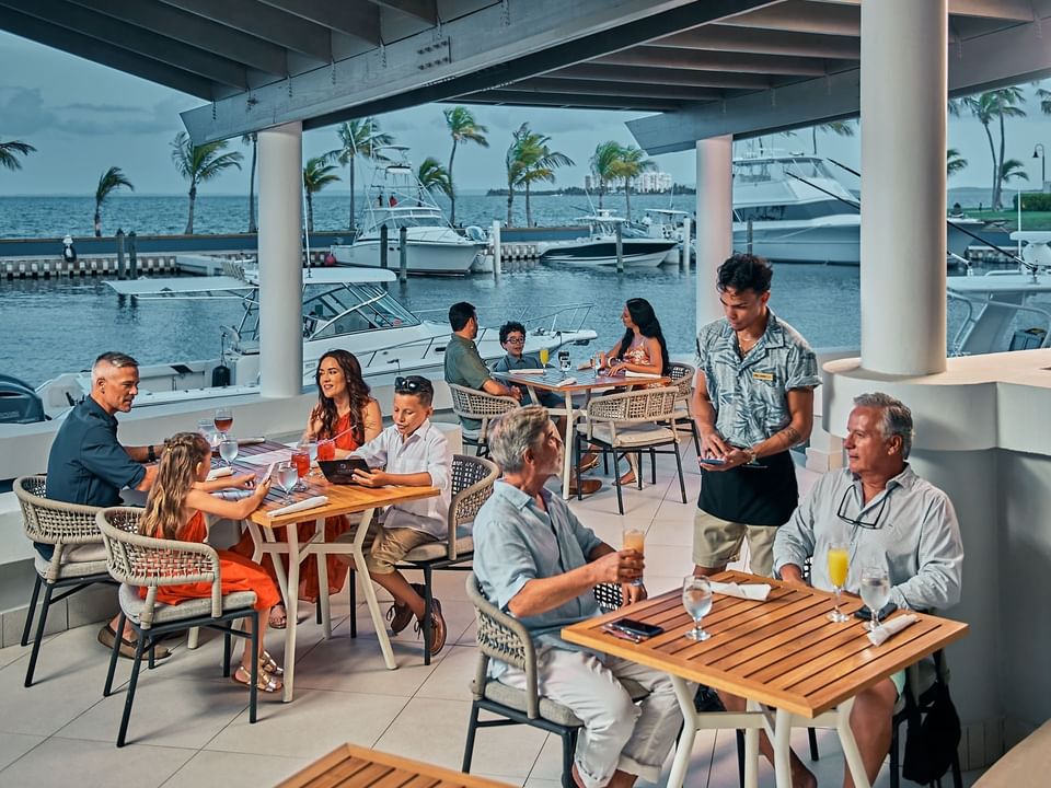 People dining with a view of the sea with docked boats in Ballyhoo at Las Casitas Village