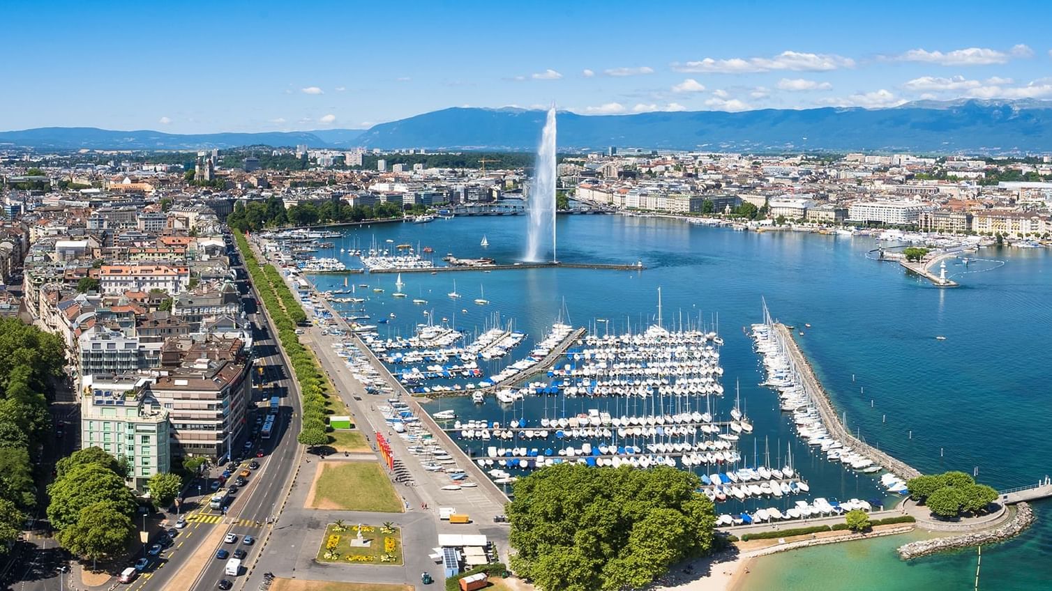 Aerial view of Lake Geneva featuring the Jet d'Eau fountain, sailboats, and the cityscape, near Warwick Hotels and Resorts