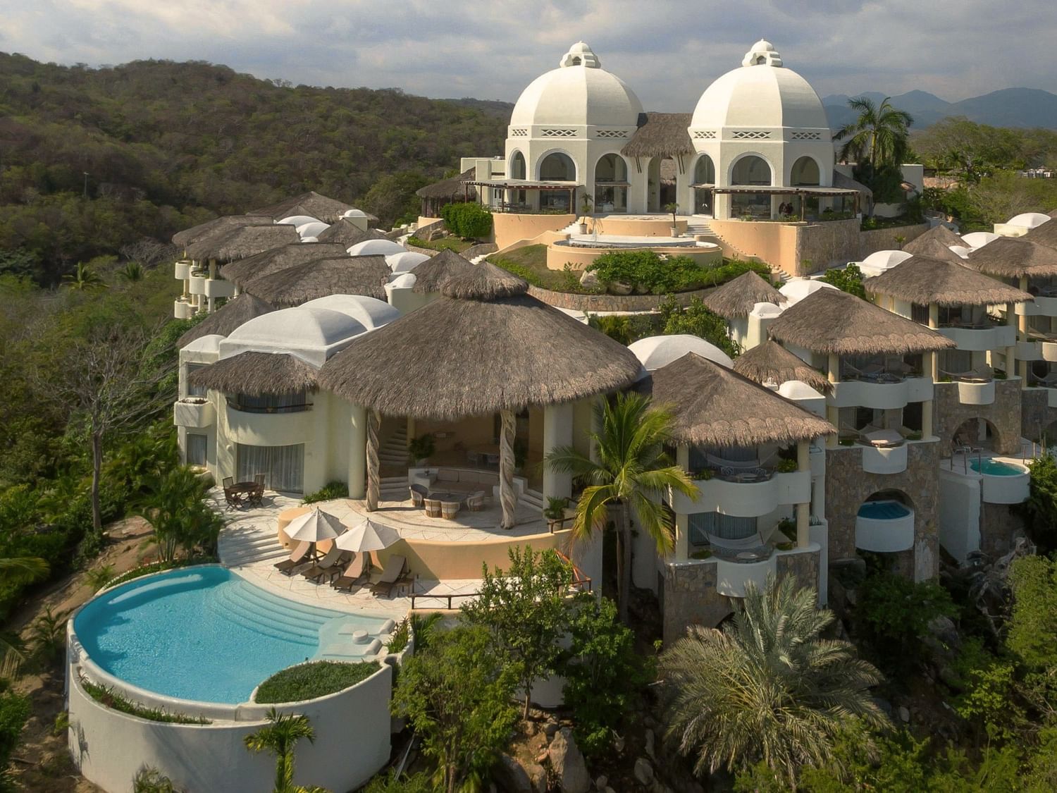 Luxury resort at Camino Real Hotels, featuring thatched roofs, white domes, and a private pool area