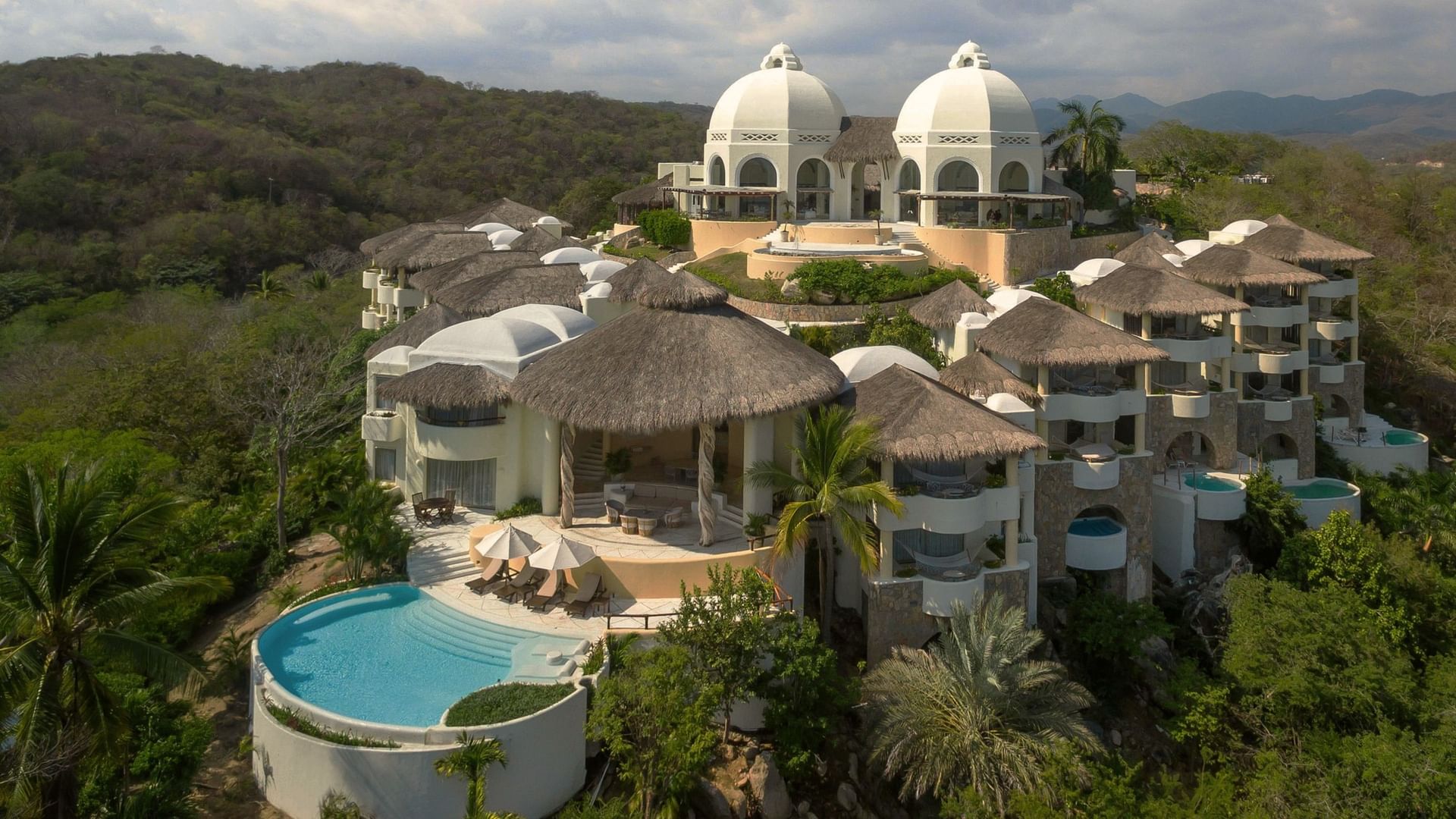 Luxury resort at Camino Real Hotels, featuring thatched roofs, white domes, and a private pool area