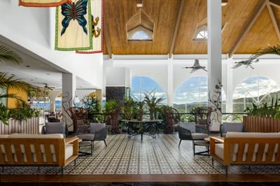 A spacious lobby area with furniture, large windows, and hanging art at Gamboa Rainforest Resort.