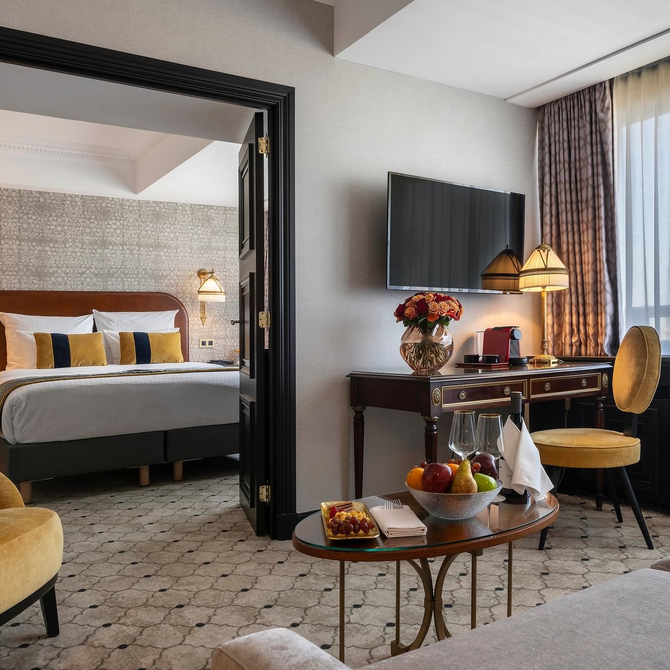 Chambre élégante avec lit, bureau, chaise, corbeille de fruits et télévision à l'hôtel Barsey by Warwick de Bruxelles.