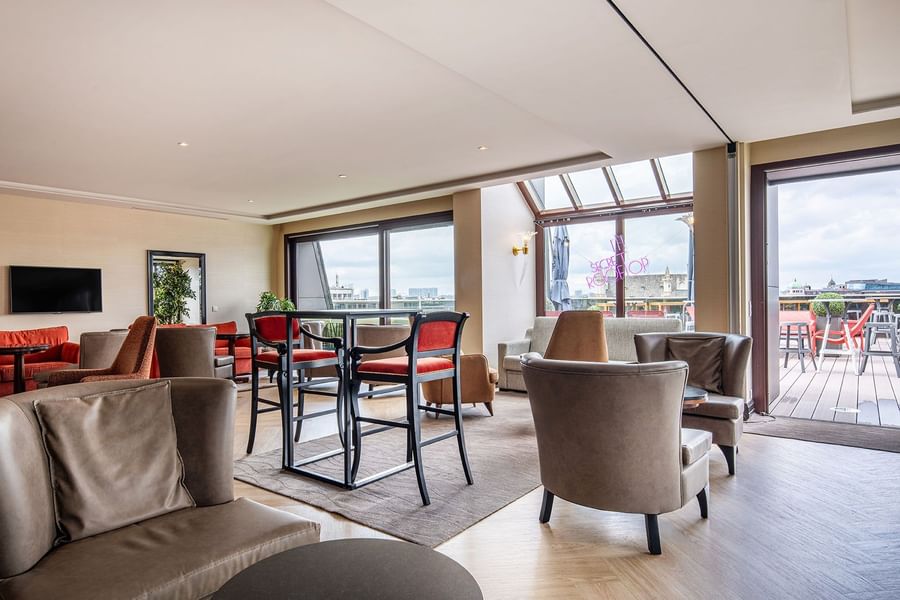 Lichte en moderne loungeruimte met banken en tafels in Warwick Grand-Place Brussels.