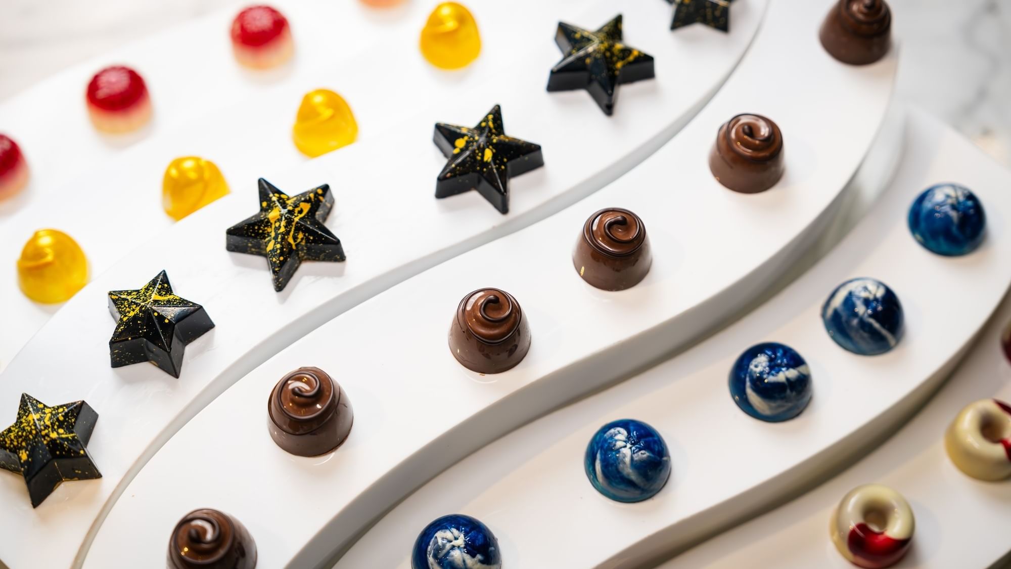 Vibrant, artistic handmade chocolates on a tiered white display at Paramount Hotel Dubai