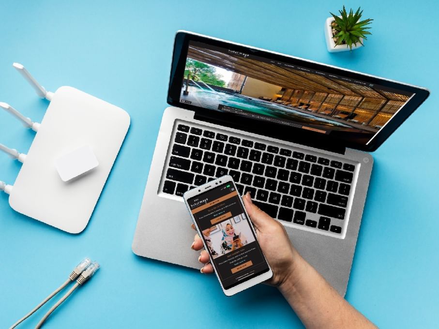 Person holding a phone, laptop & accessories on a blue background at Hotel Maya Kuala Lumpur City Centre