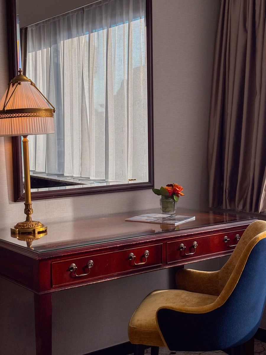 Close up of wooden work desk with gold lamp and fresh flower vase in Deluxe Room at Hotel Barsey by Warwick