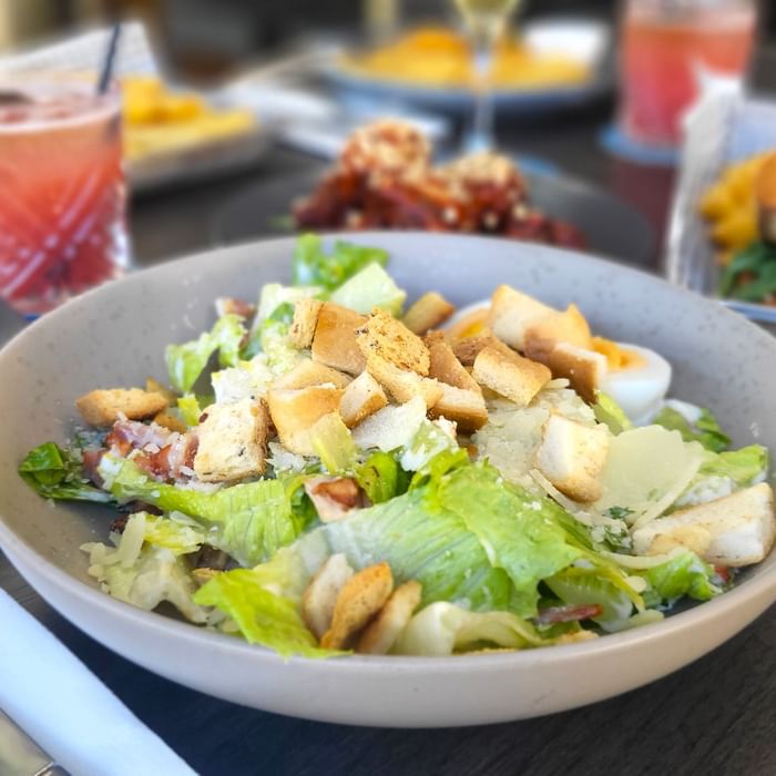 Caesar Salad with drinks served on a table in Celsius Restaurant & Bar at Mercure Hotel Townsville