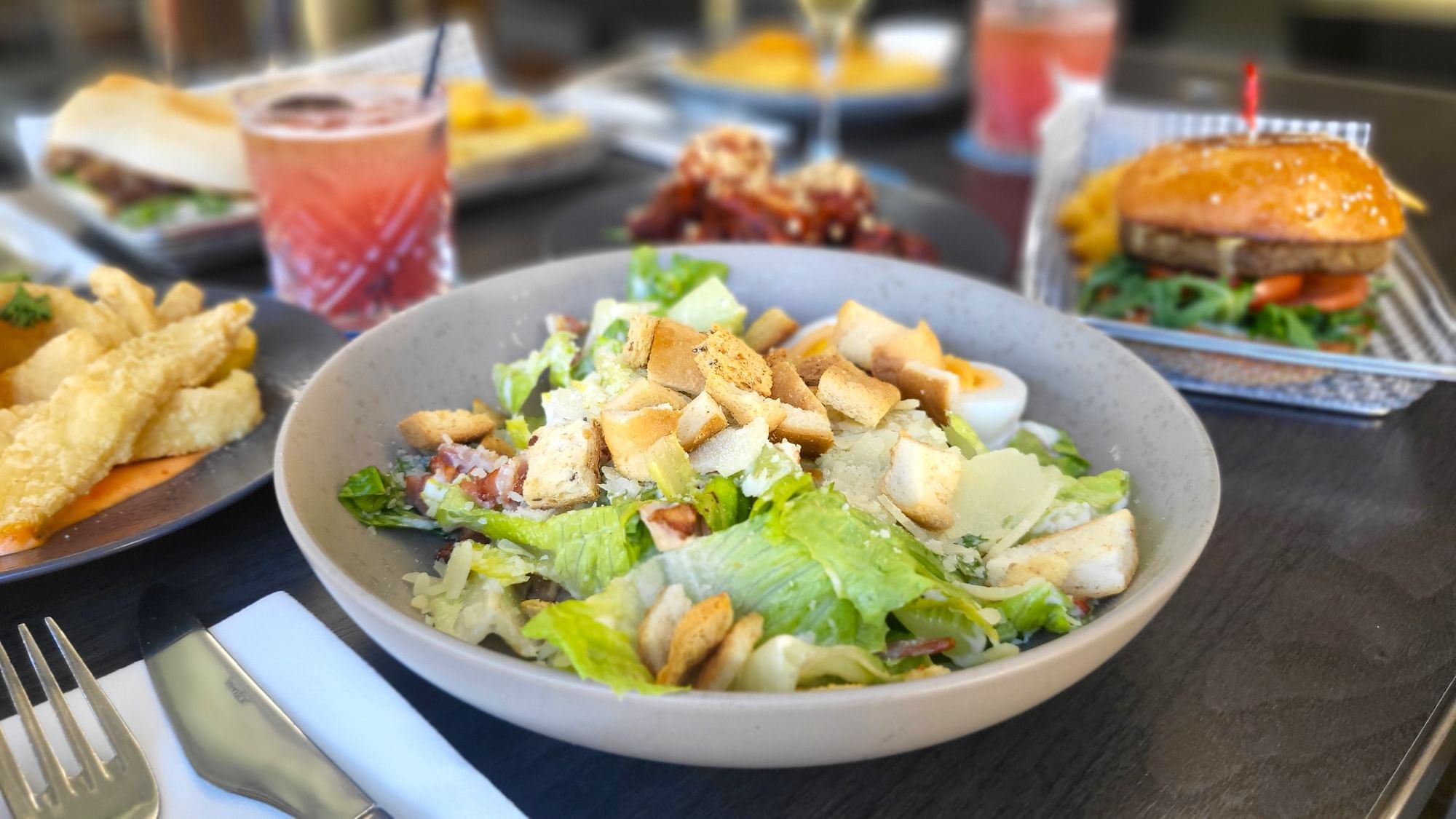 Caesar Salad with drinks served on a table in Celsius Restaurant & Bar at Mercure Hotel Townsville