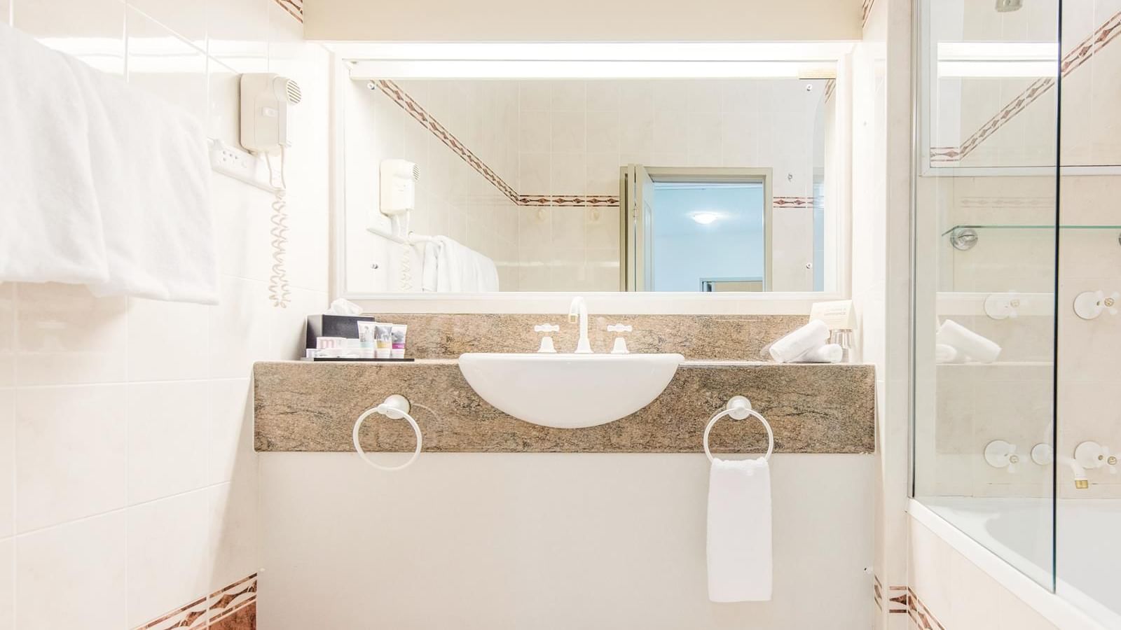 Marbled bathroom vanity area with a bathtub in Privilege King at Mercure Charlestown