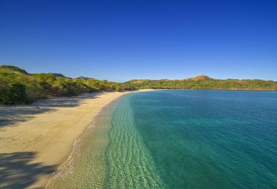 A calm beach with hills in Playa Conchal near Villas Sol Beach Resort