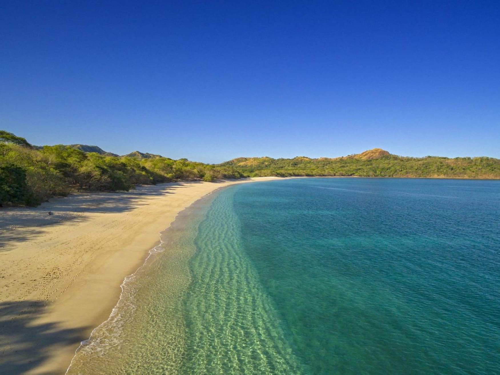 A calm beach with hills in Playa Conchal near Villas Sol Beach Resort