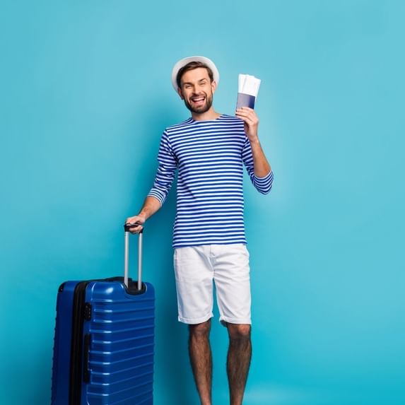 A man holding a travel bag & passport at Village Hotels