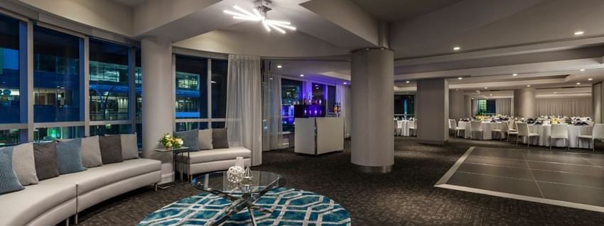 Ballroom with a curved sofa and geometric rug placed by large windows at Warwick Le Crystal Montreal