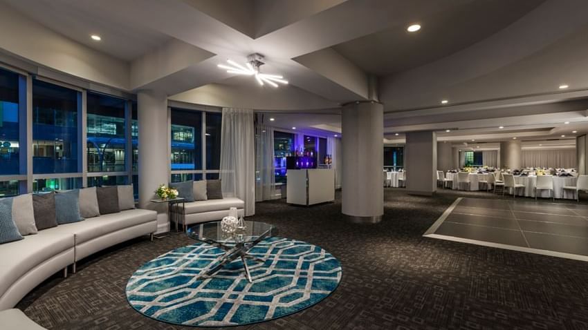 Ballroom with a curved sofa and geometric rug placed by large windows at Warwick Le Crystal Montreal
