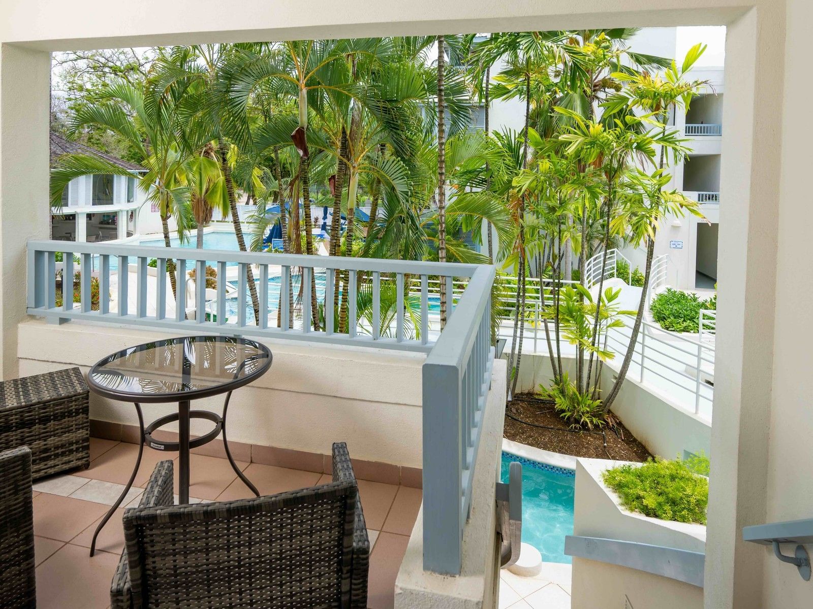 Private terrace with wicker seating and direct pool access steps surrounded by tropical palms at Savannah Beach Hotel