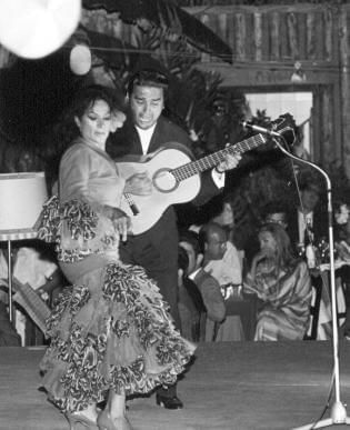 Man playing guitar & a lady dancing on a stage at Marbella Club