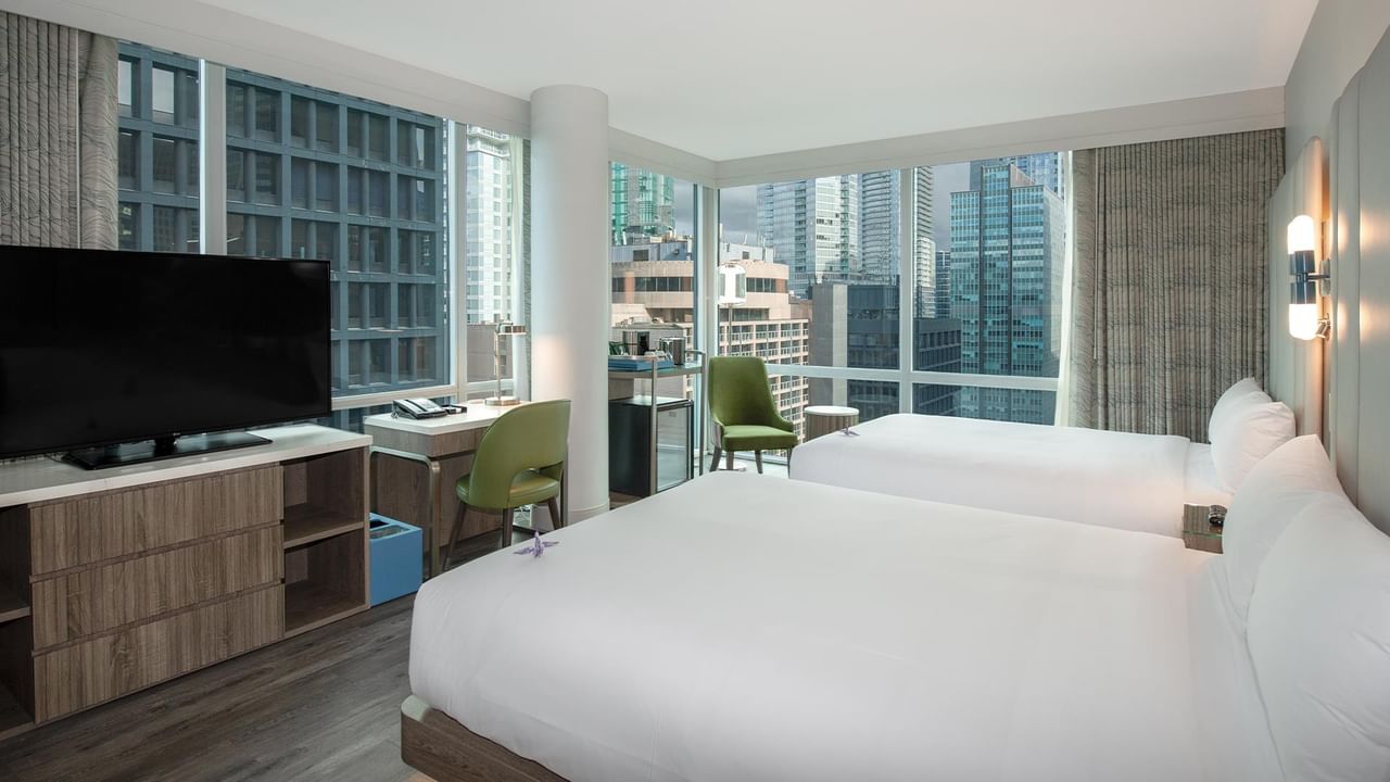 Hotel room with two beds, a desk, and a large TV.
