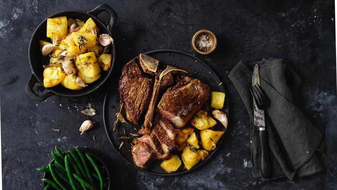 Perfectly cooked sliced T-bone steak with roasted potatoes at Steak & Oyster Co. by Sean Connolly in Novotel Sydney