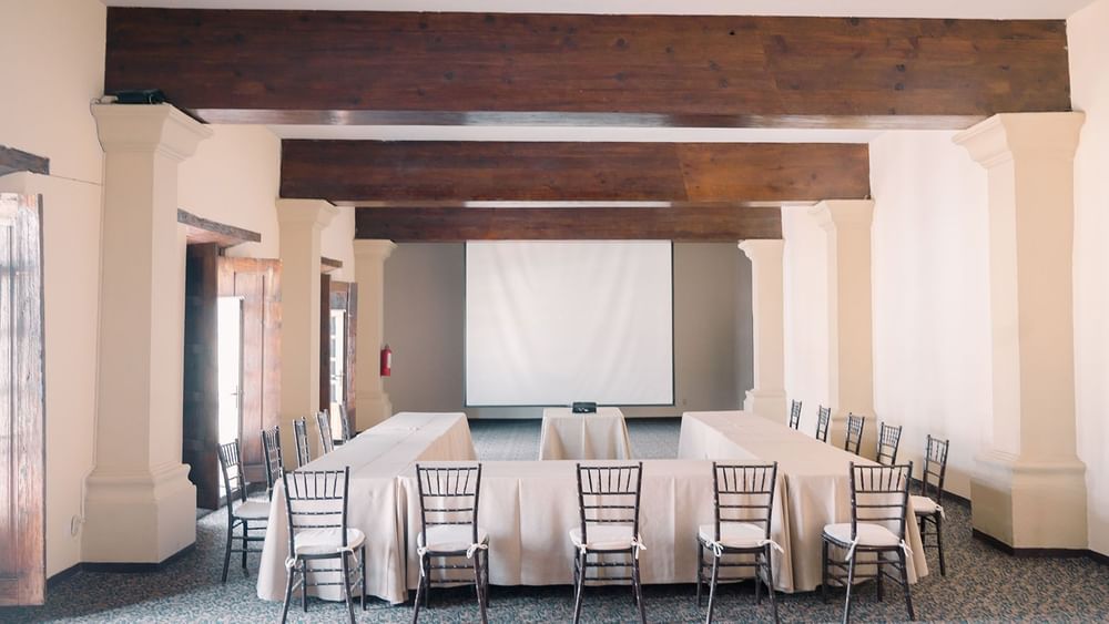San Pedro seminar room featuring heavy wooden beams and a large projector screen at Quinta Real Zacatecas