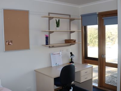 Desk with chair, bulletin board, and shelves in a room at La Trobe University - Terraces.
