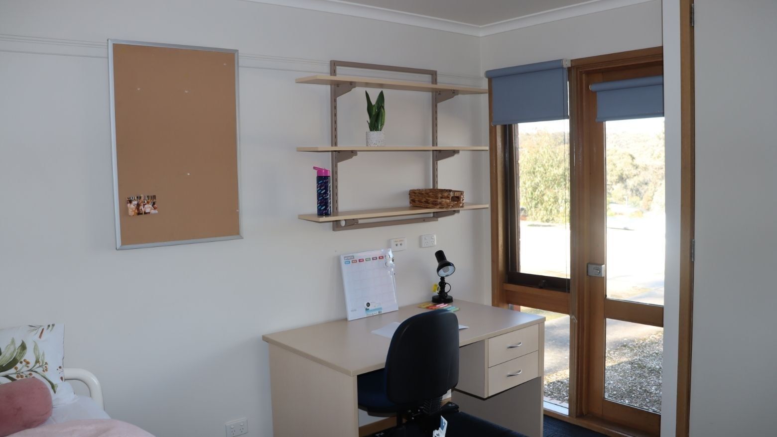 Desk with chair, bulletin board, and shelves in a room at La Trobe University - Terraces.