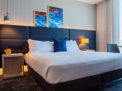 Bravo Suite featuring a plush bed with side table and abstract art on the wall at Encore By Mingara