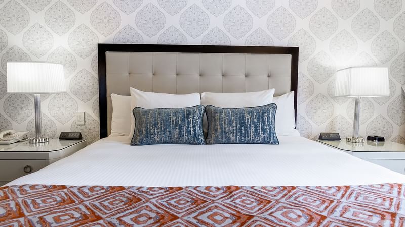 Cozy bed with side tables and working table in On The Avenue One Bedroom Suite at Warwick New York