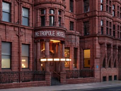 Grand Victorian red-brick entrance of The Met Hotel Leeds, England, featuring the original carved Metropole Hotel sign