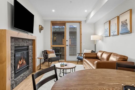 Modern living room with leather sofa, fireplace and wall-mounted TV at Spring Creek Canmore Vacation Rentals