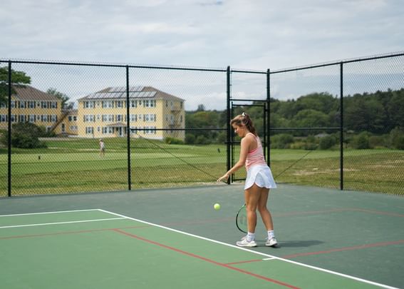 Lady playing in an outdoor tennis court by the golf course at Sebasco Harbor Resort