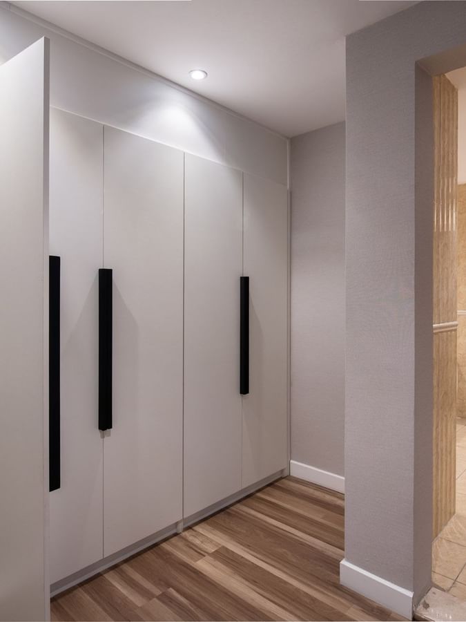 White wardrobes with black handles by a bathroom entrance with a marble vanity in Royal Suite Sea View at Warwick Al Jubail