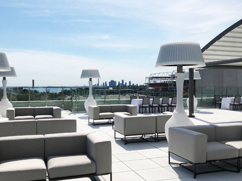 Outdoor rooftop terrace with grey modular sofas and tall white floor lamps facing city skyline view at Hotel X Toronto