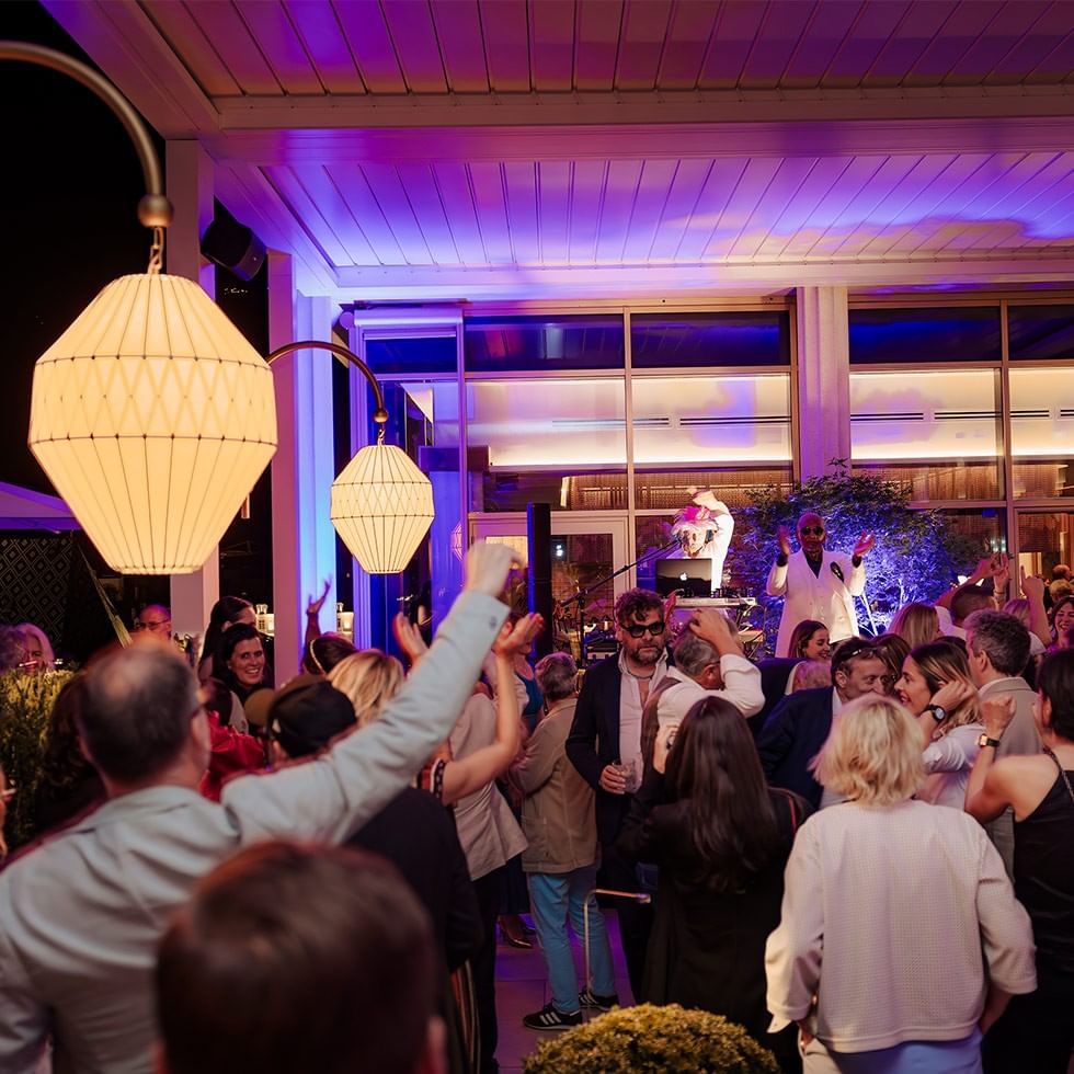 Gäste feiern auf einer Terrassen-Eröffnungsparty mit bunten Lichtern und Musik.
