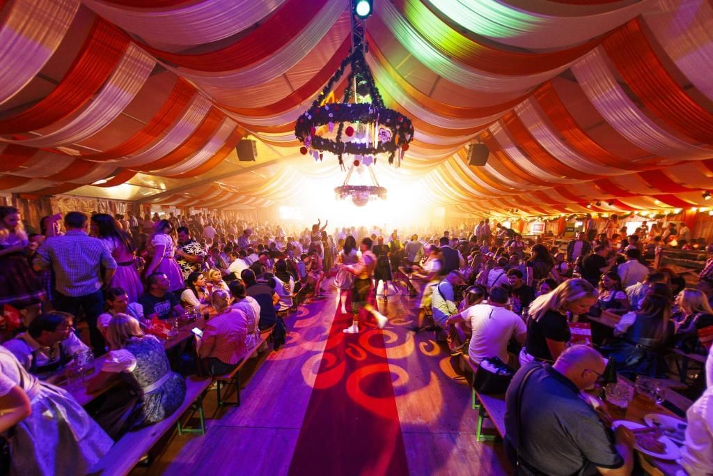 Kaiser Wiesn in Vienna with a festively lit tent, dancing guests and a lively Oktoberfest atmosphere